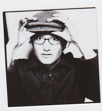 Schwarz-weiss-Foto einer jungen Frau mit Brille und Hut schaut erschrocken.