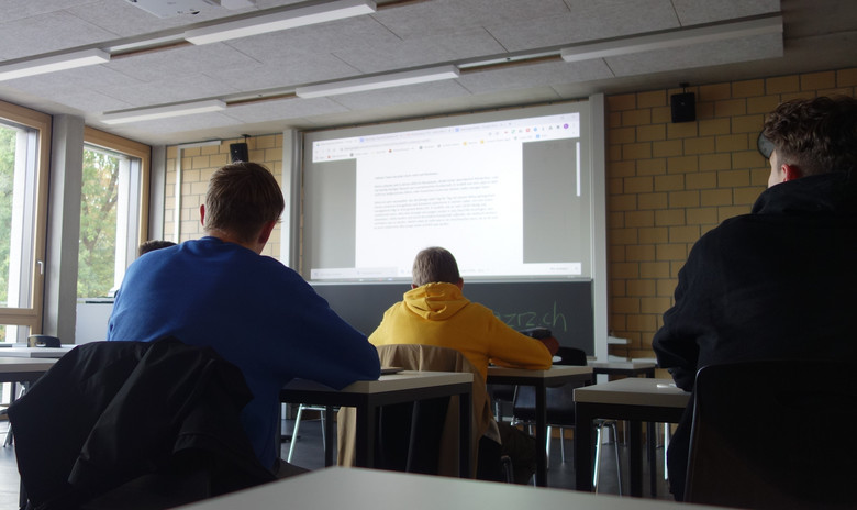 Schüler sitzen im Schulzimmer und blicken auf die Tafel.