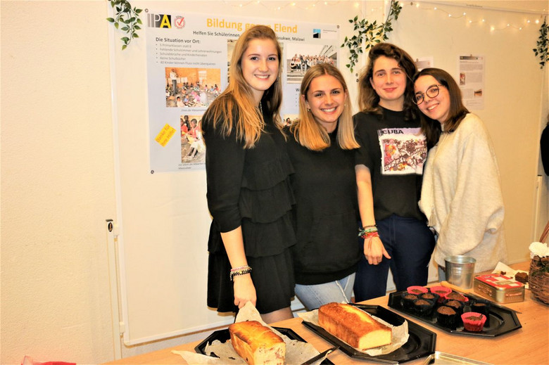 Vier junge Frauen verkaufen Kuchen. 