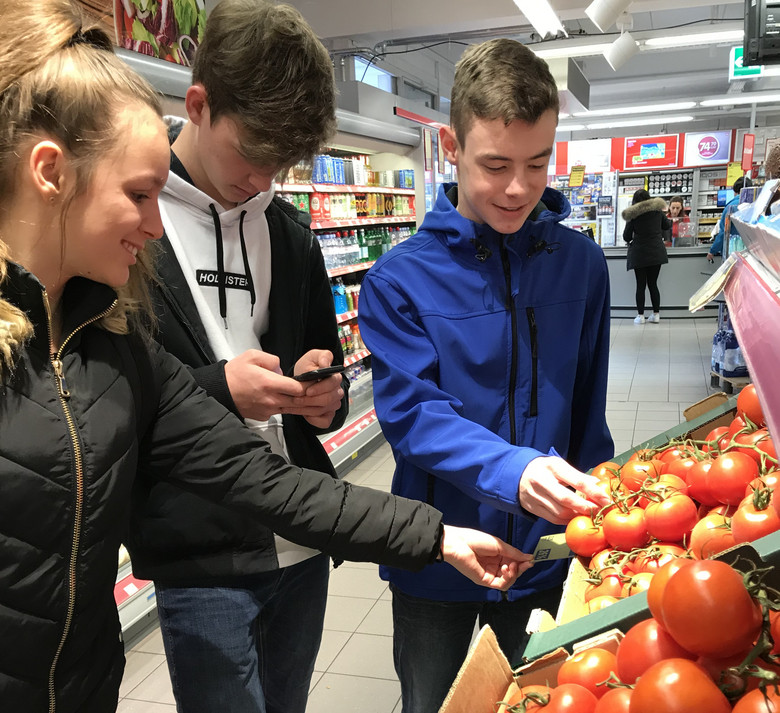 Jugendliche betrachten Tomaten in einem Supermarkt.