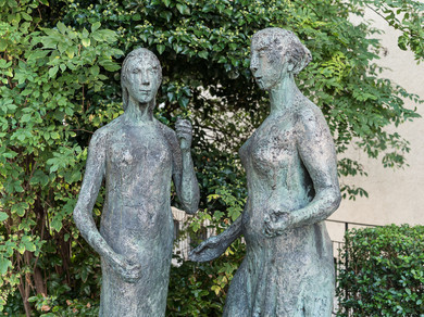 Zwei weibliche Statuen stehen in einem Garten. 