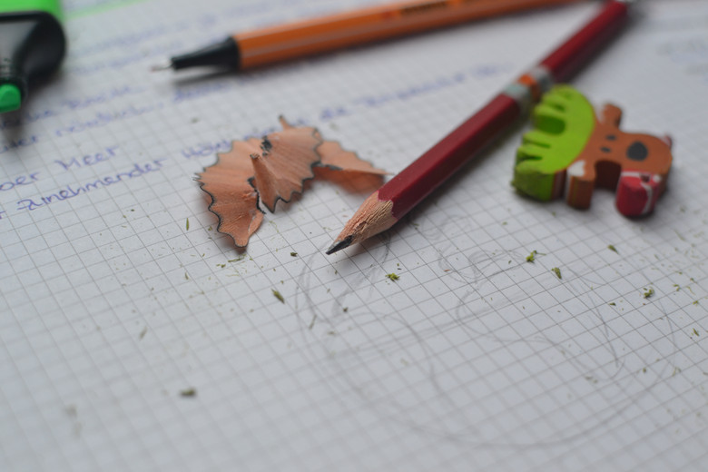Angespitzte Bleistifte, ein Radiergummi und ein Marker liegen auf einem Blatt Papier. Eine Nahaufnahme. 