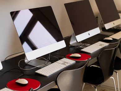 Apple-Computer stehen nebeneinander auf einem Schreibtisch.
