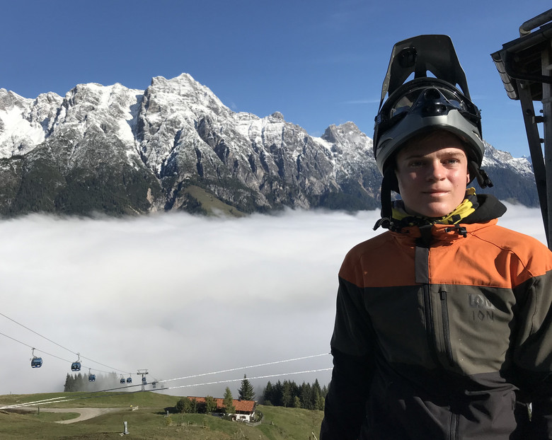 Ein Junge mit Fahrradhelm vor nebligen verschneiten Bergen.