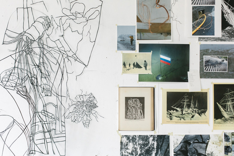 Papierschnitt und diverse Fotos an einer Wand.