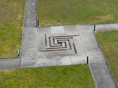 Labyrinth aus Beton umgeben von Gras.