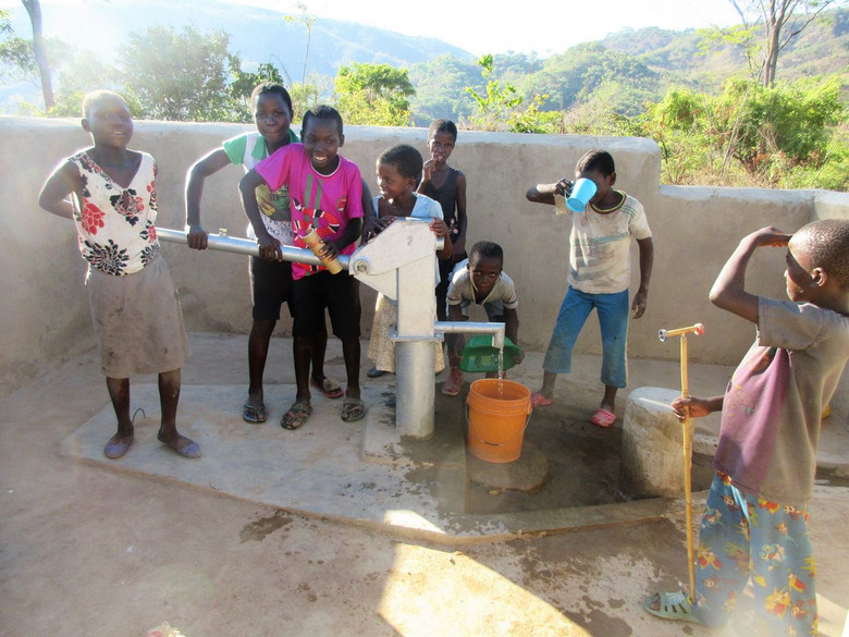 Kinder stehen um einen Brunnen in Mwasukwe, Malawi.