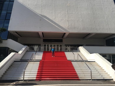 Eine junge Frau steht auf einer Treppe vor einem Gebäude auf einem roten Teppich.